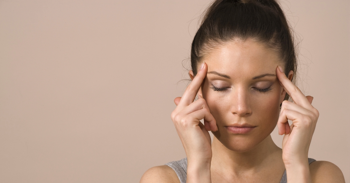 woman touches head with eyes shut