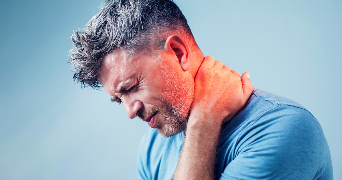 up close left side view of mans face in pain holding left arm to back of neck pain